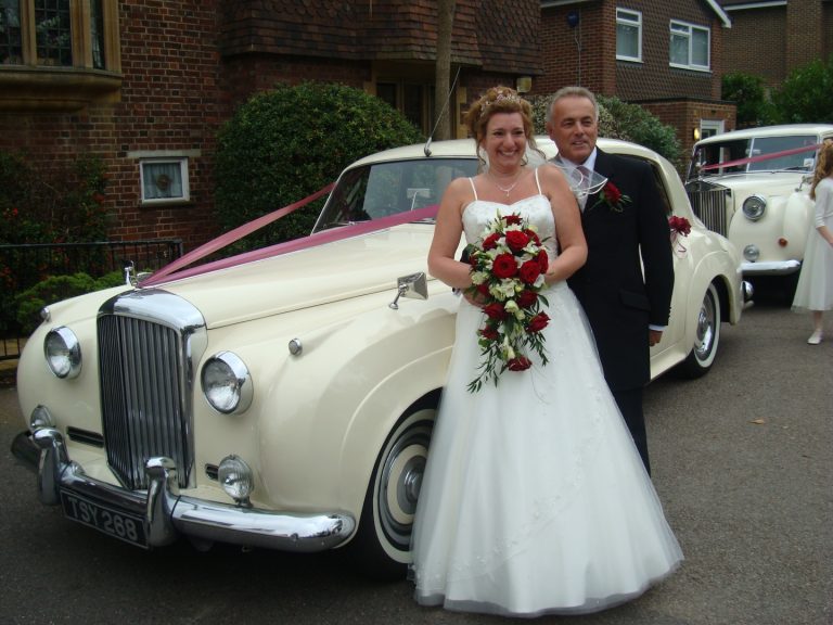 The front of a white Bentley S1 decorated with a white ribbon for a wedding.