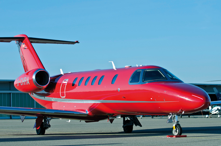 A red and white Citation CJ4 private jet on an airfield tarmac.