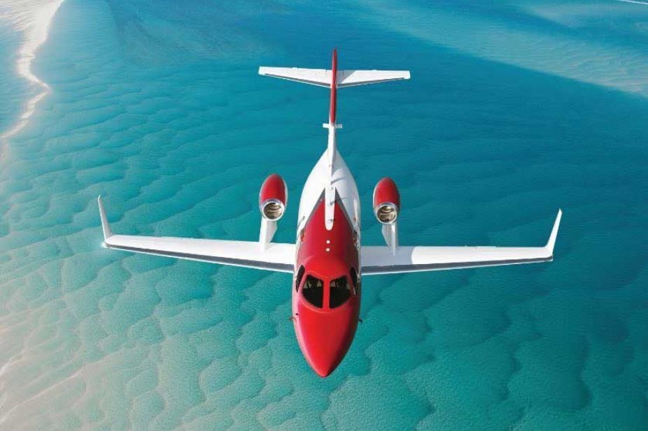 A HondaJet flying through a clear blue sky, showcasing its unique over-the-wing engine mounts.