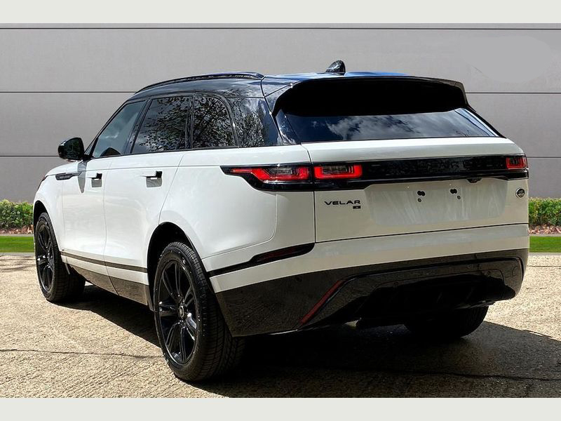 A professional chauffeur waiting by a Range Rover Velar.